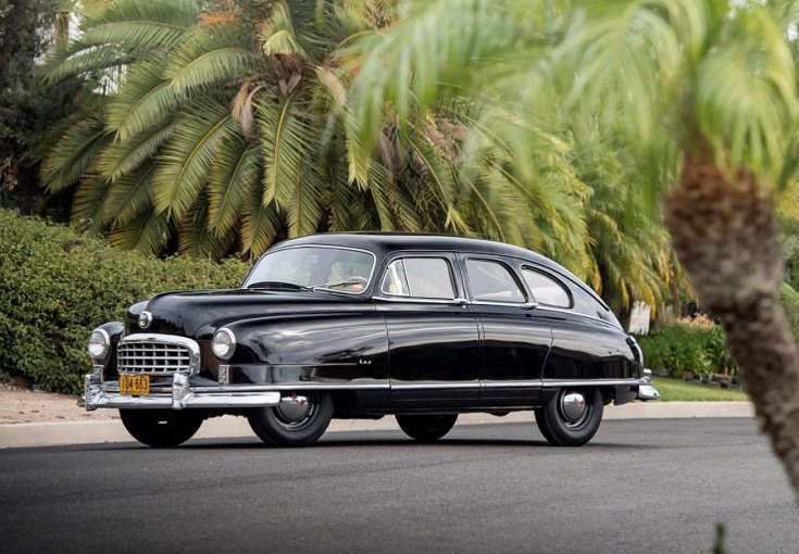 1949 Nash Airflyte Statesman, fekete fastback limuzin, elölnézet, oldalnézet, balról döntve, alulról fotózva, háttérben lejtős kert, a képen jobbra pálmafa