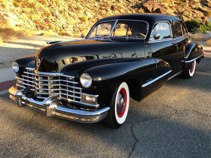 1946 Cadillac 60 Special, fekete hosszított limuzin, elölnézet, oldalnézet, balról döntve, alulról fotózva, fehérfalú gumik piros belső peremmel, osztott szélvédő, háttérben őszi tájkép