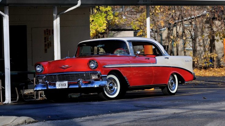 1956 GM Chevrolet Bel Air, kéttónusú piros 4 ajtós hardtop limuzin, fehér fenék, hátsórész és tető, elölnézet, oldalnézet, balról döntve, távolról fotózva, alulnézetből