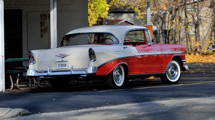 1956 Chevrolet Bel Air, kéttónusú piros 4 ajtós hardtop limuzin, fehér fenék, hátsórész és tető, hátulnézet, oldalnézet, jobbról döntve, távolról fotózva, alulnézetből