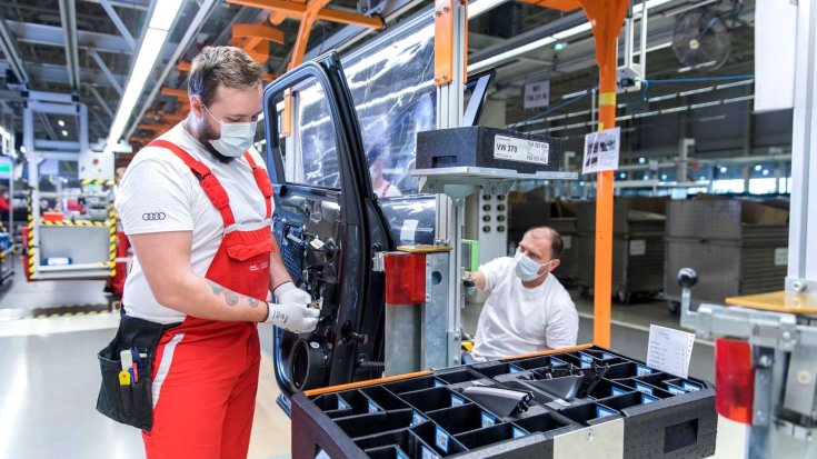 Munkások dolgoznak szájmaszkban a győri Audi-gyárban