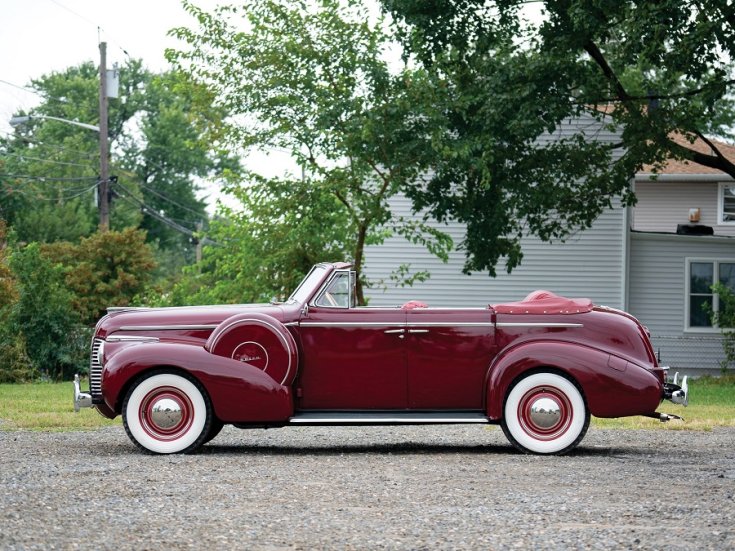 1940 Buick Special Sport Phaeton, meggyvörös kabrió limuzin, oldalnézet, balról, alulról fotózva, háttérben fák és házak