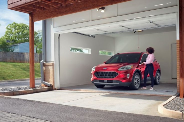 Plug-in hibrid Ford Kuga modell egy garázsban állva egy családi háznál, elölről