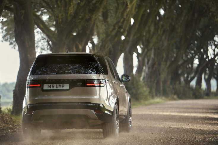 2020-as frissített Land Rover Discovery modell vidéki úton menet közben hátulról