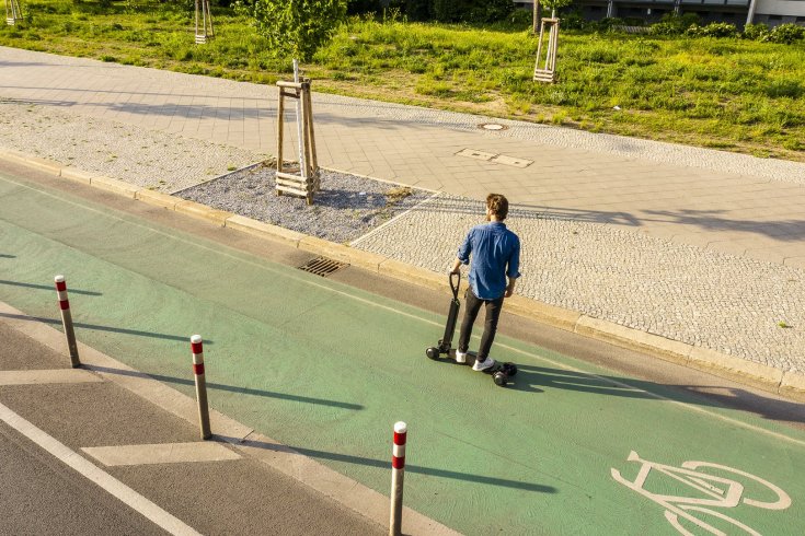 Egy kézzel vezeti egy férfi az Audi elektromos rollerét