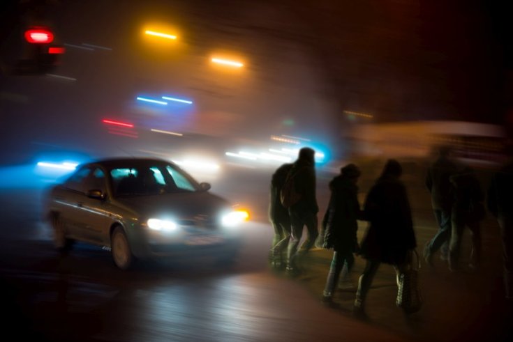 gyalogosok sétálnak át az úton egy autó előtt éjszaka