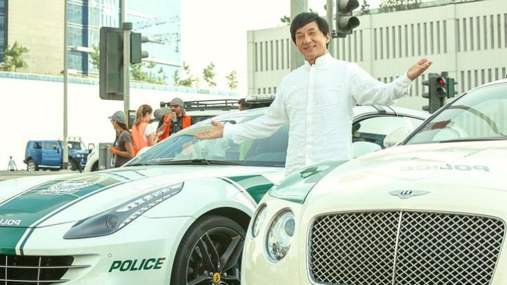 Jackie Chan két autó között áll
