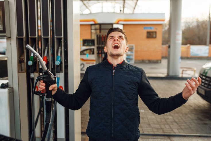 fotó egy ideges emberről, aki a benzinkúton áll egy töltőpisztollyal a kezében