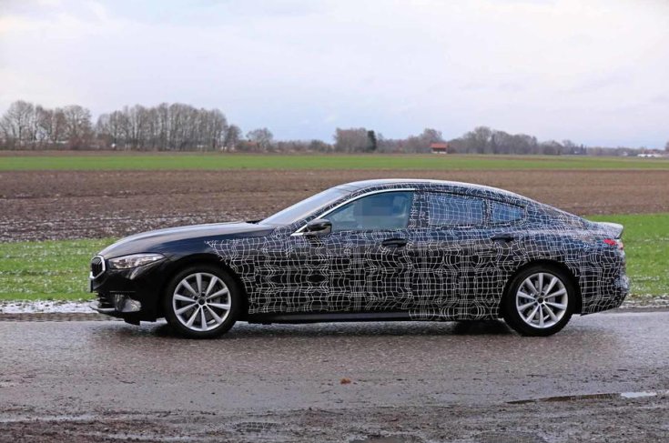 A 2019-es BMW 8 Gran Coupé álcázott prototípusa oldalról fotózva egy réten