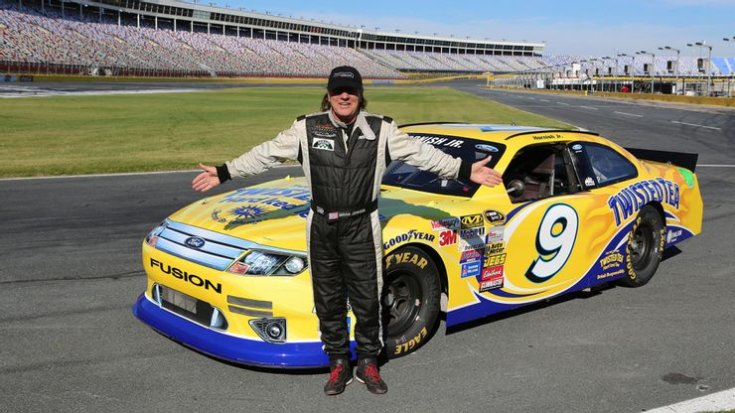 Brian Johnson egy Nascar autó mellett egy oválpályán