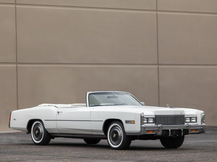 1975 Cadillac Eldorado Biarritz, fehér kabrió, lehúzott tető, elölnézet, oldalnézet, jobbról döntve, betonfal háttér, távolról fotózva, ráközelítve