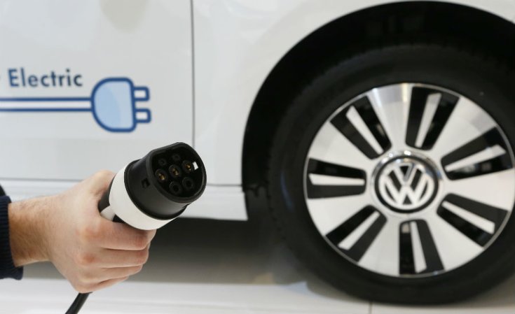 Egy elektromos rendszerrel rendelkező Volkswagen töltő egy autóval háttérben