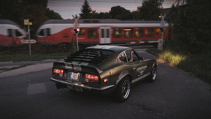 1972 Datsun S30 hátulról elsuhanó vonattal a háttérben