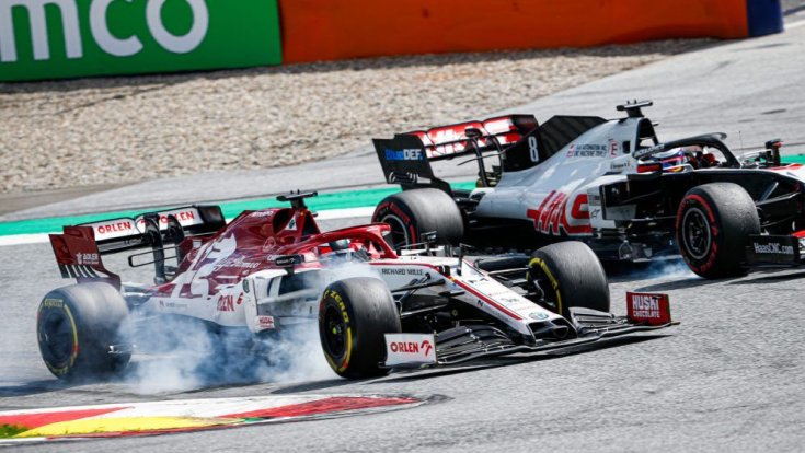 füstölve fékező Alfa Romeo, mellette egy Haas