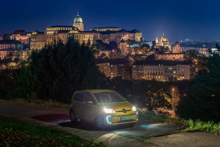 fotó egy arany színű, világító lámpájú greengo autómegosztó szolgáltató által üzemeltetett Volkswagen e-Up! villanyautóról a budapesti éjszakában