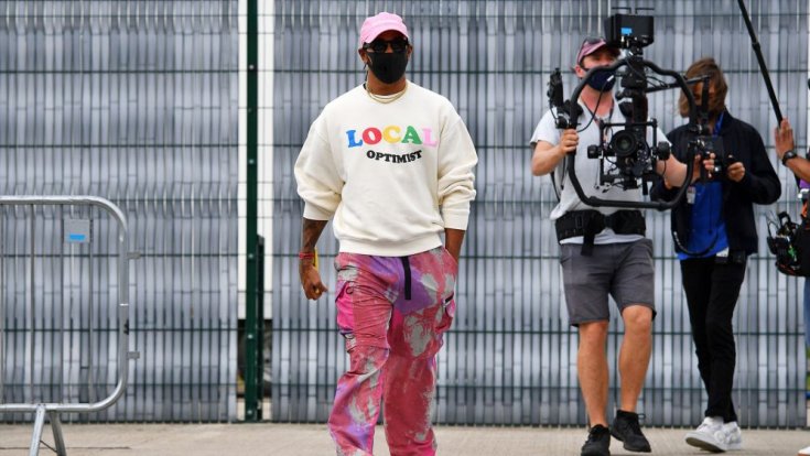 Lewis Hamilton érdekes ruhában kamerás emberek mellett