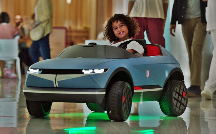 Mini villanyautó volánjánál ülő beteg kisgyermek