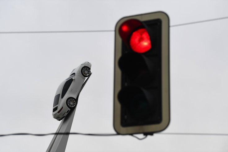Porsche autó az előtérben egy pirosan világító közlekedési lámpával