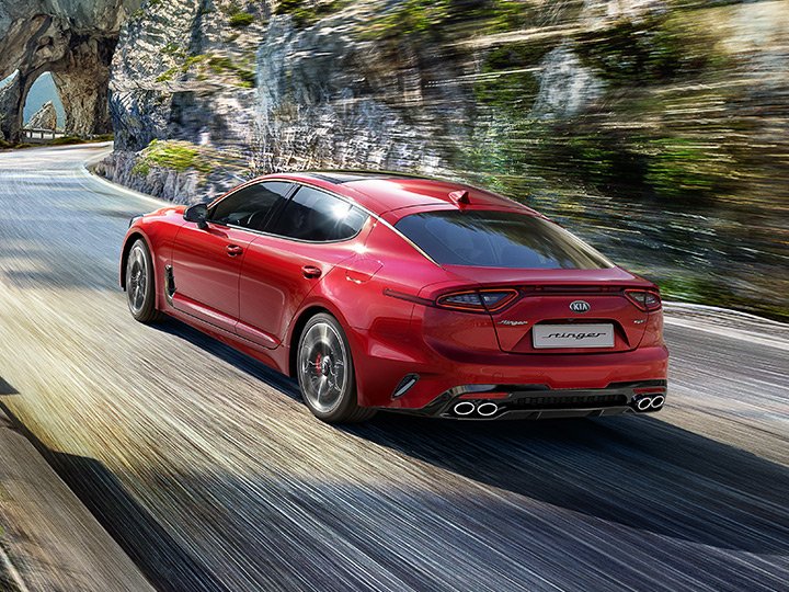 Piros Kia Stinger, négy kipufogóvéggel, oldalról, hátulról fotózva egy szerpentinen