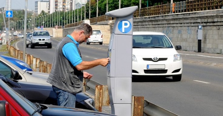 Pénzt dob a parkolóautomatába egy férfi Budapesten
