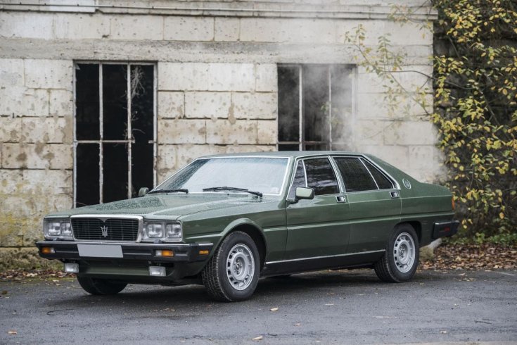 Olivazöld színű Maserati Quattroporte egy kőház előtt, szemből, oldaltról fotózva