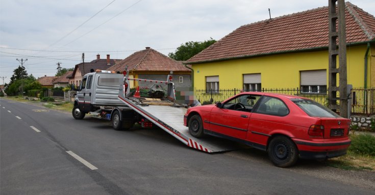 fotó egy trailer platójára felkúszó piros BMW E36 compact autóról