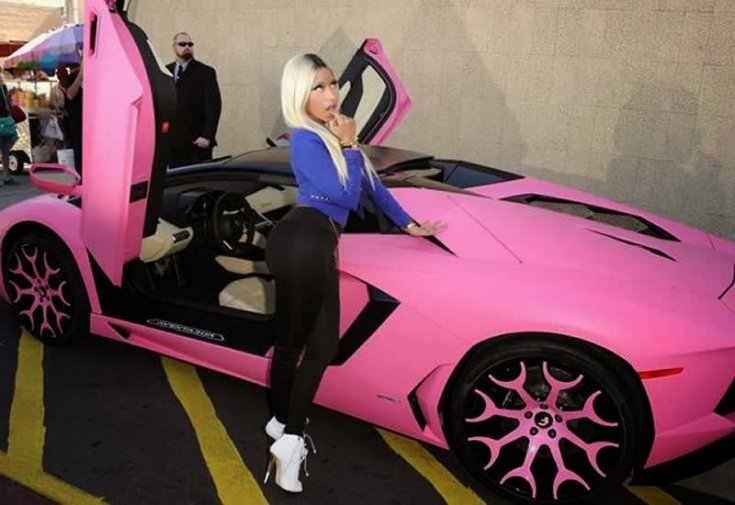 Nicki Minaj egy rózsaszín Lamborghini Aventador mellett egy parkolóban, féloldalról