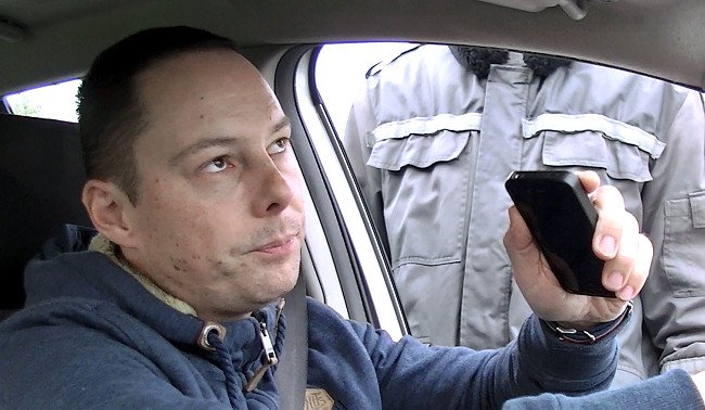 Autóvezető mobillal a kezében, mellette egy rendőr