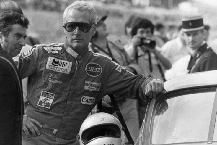 Paul Newman egy versenyen az autónak támaszkodva, elölről