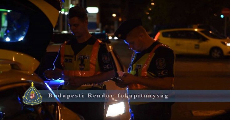 Rendőrök ellenőriznek egy autót a budapesti éjszakában