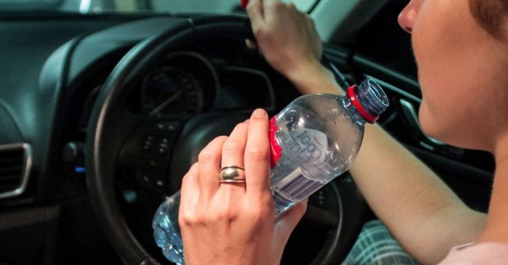 Vezetés közben vizet kortyolgató sofőr