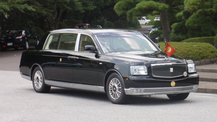 Fekete színű, fellobogózott Toyota Century szemből, oldalról