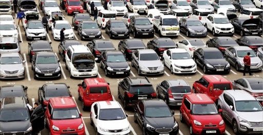 Használtautók egy hatalmas parkolóban egymás mellett