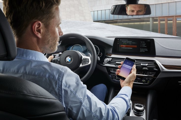 BMW sofőr kezében mobiltelefonnal