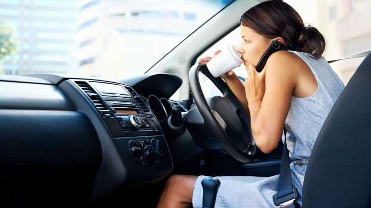 Vezetés közben ivó és telefonáló nő